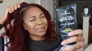 A head shot of an African American woman struggling to pull her lace front wig off and holding a bottle of Got 2 Be Glued edge control gel. 