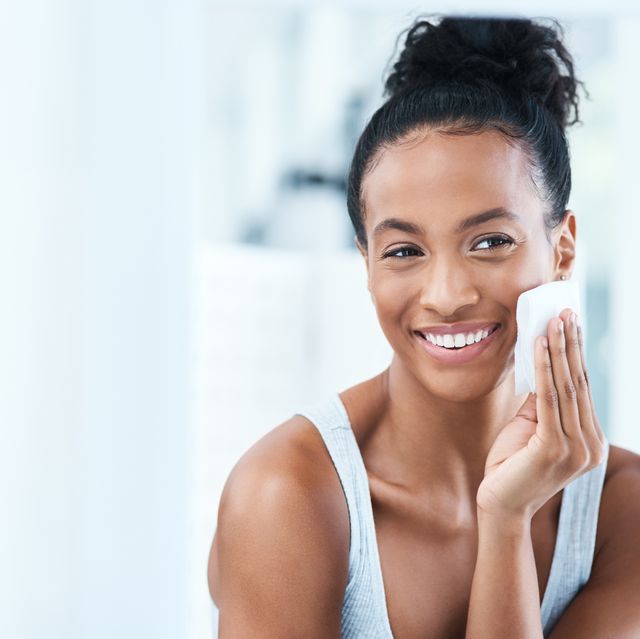 Woman of color wiping her face with a white cloth and smiling.